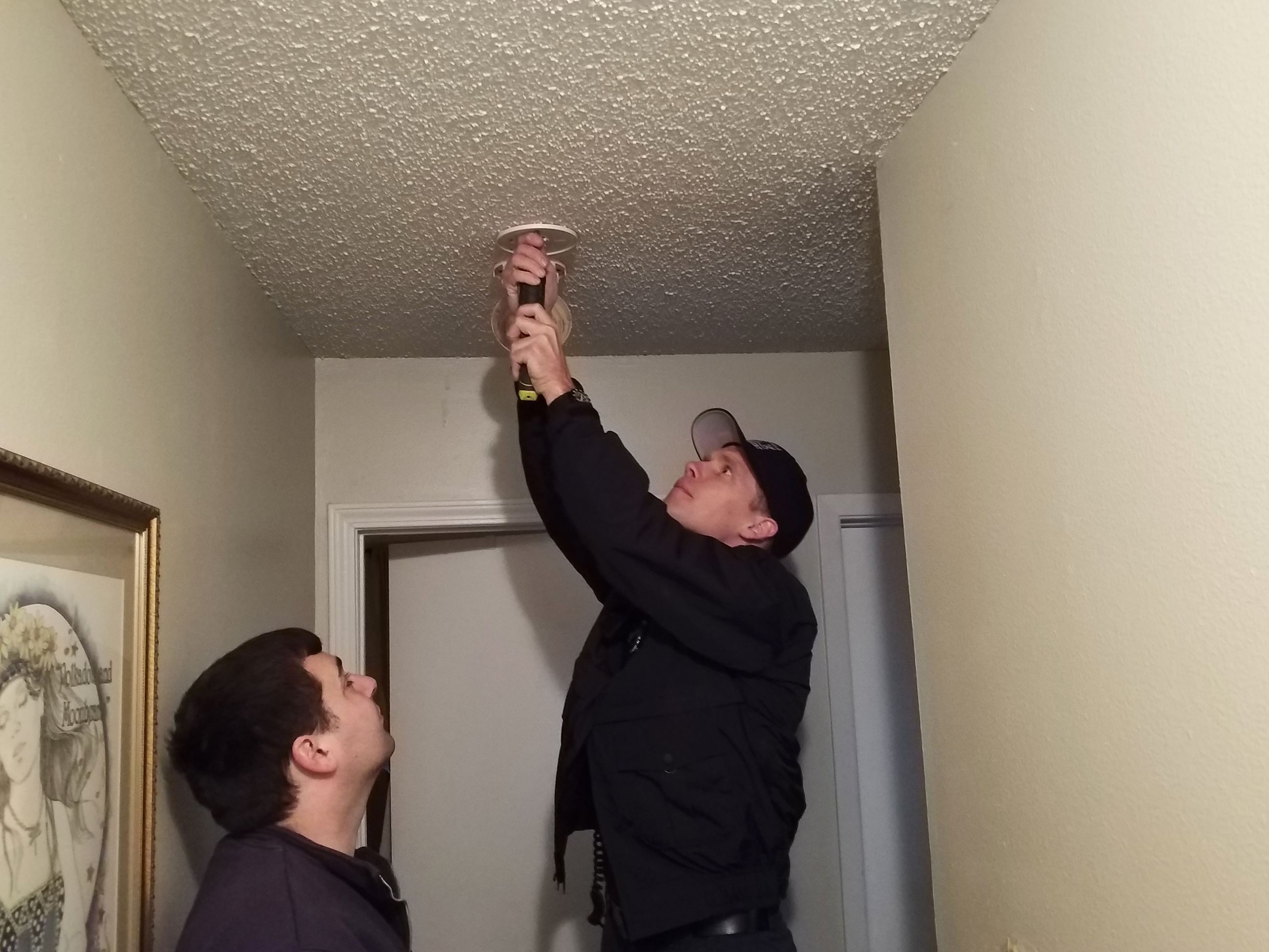 Two firefighters install a smoke alarm in a home