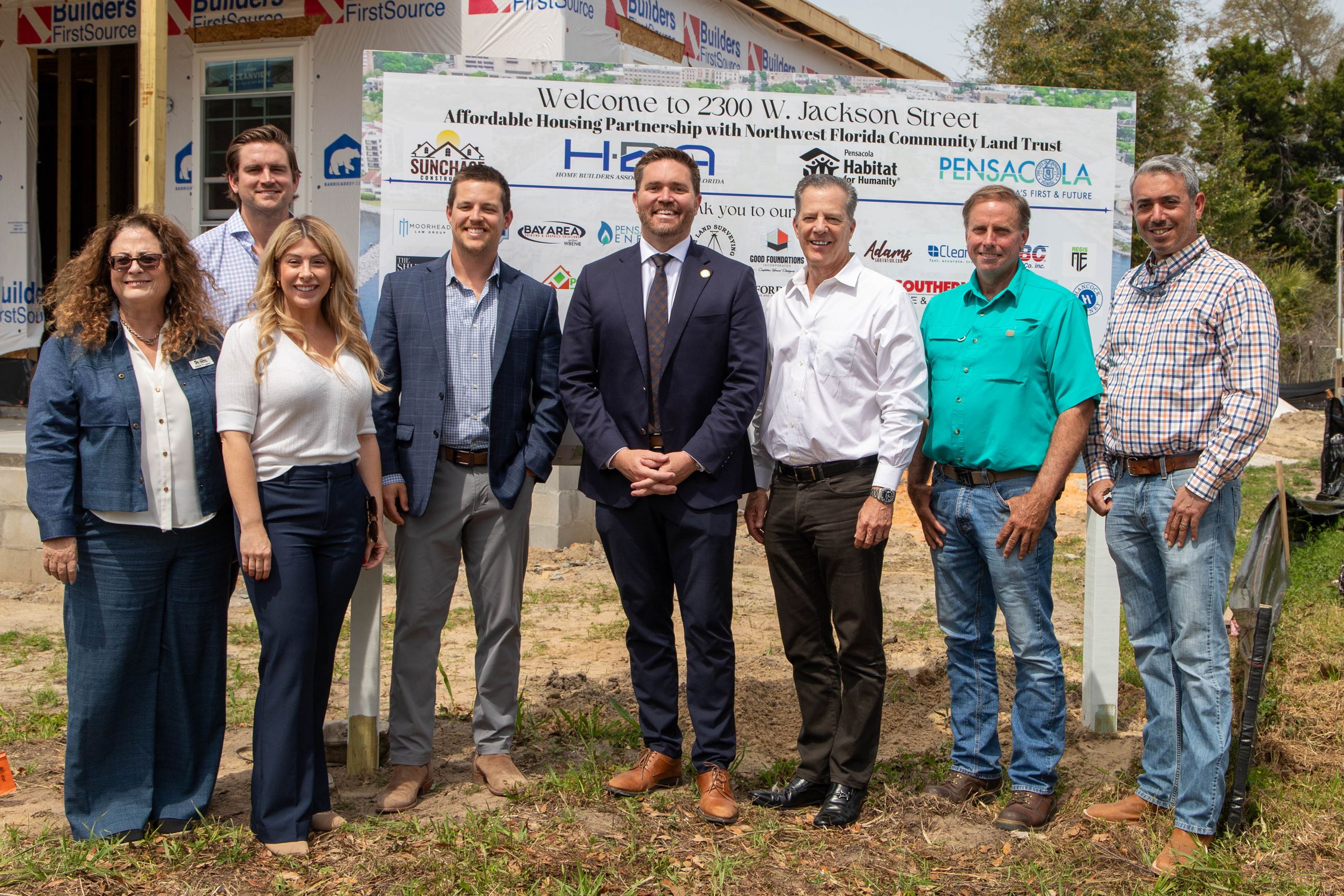 Representatives of partnership in front of sponsorship sign